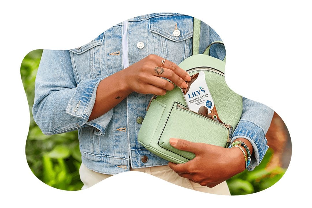woman pulling pack of lilys milk chocolate style peanut butter cups out of backpack
